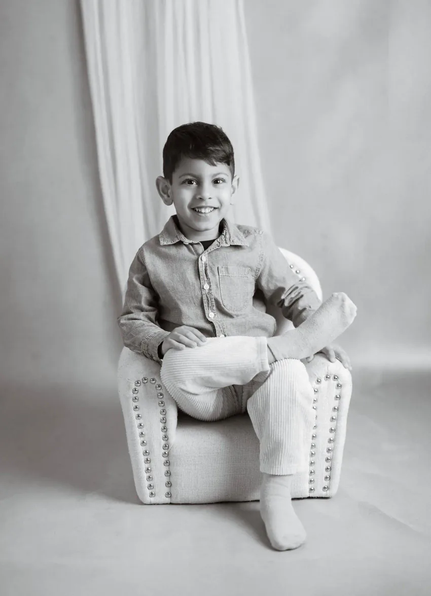 Black and white portrait of a young boy sitting in a small armchair