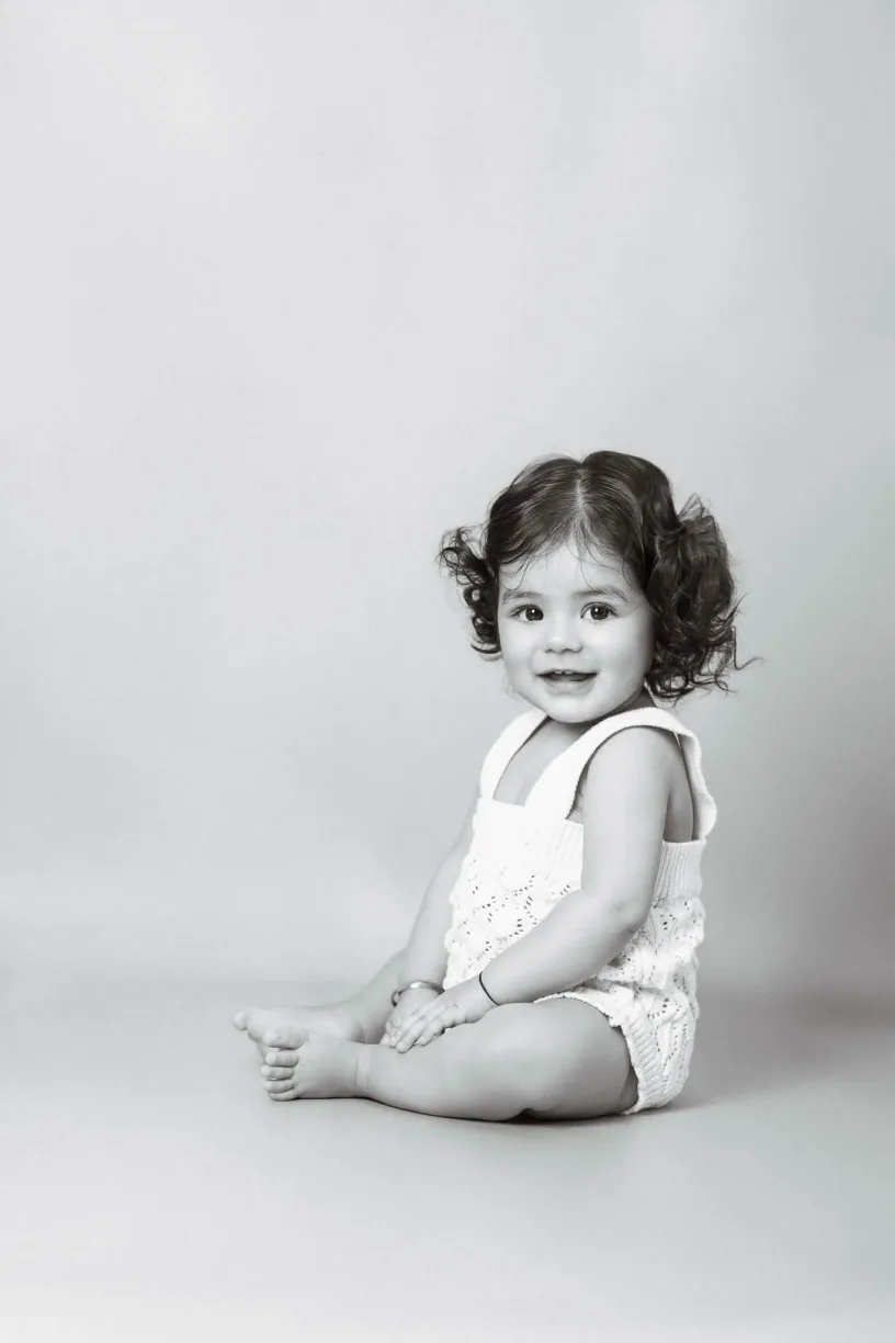 Black and white portrait of a young girl sitting against a light backdrop