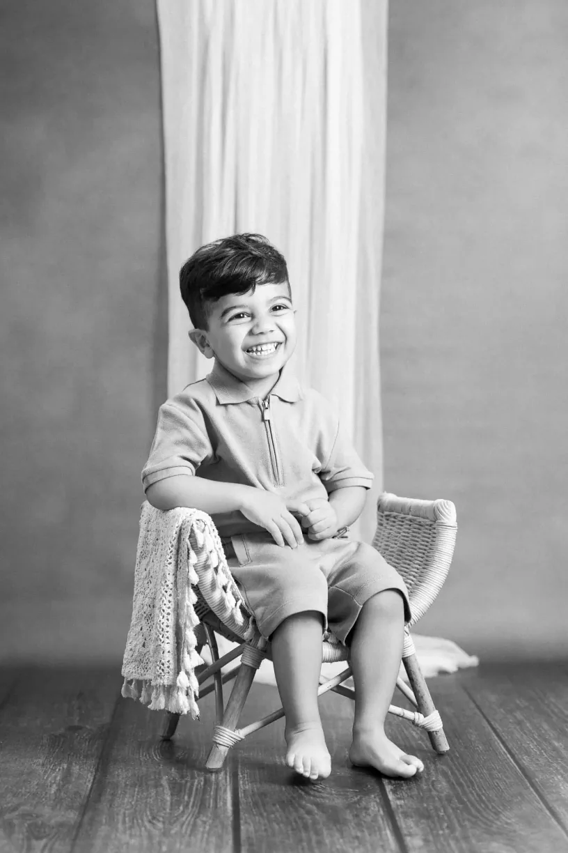 Black and white photograph of a boy seated in a small chair