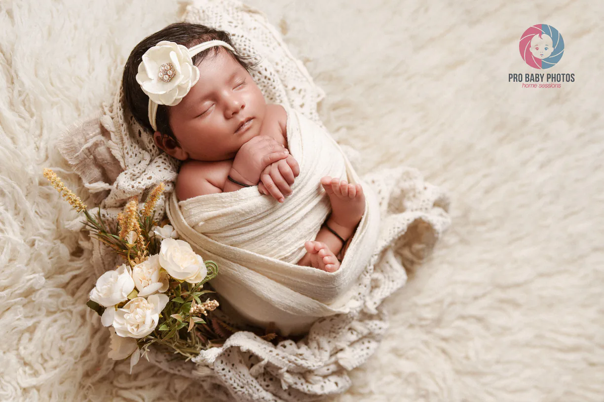 Sleeping newborn baby wrapped in a basket surrounded by flowers