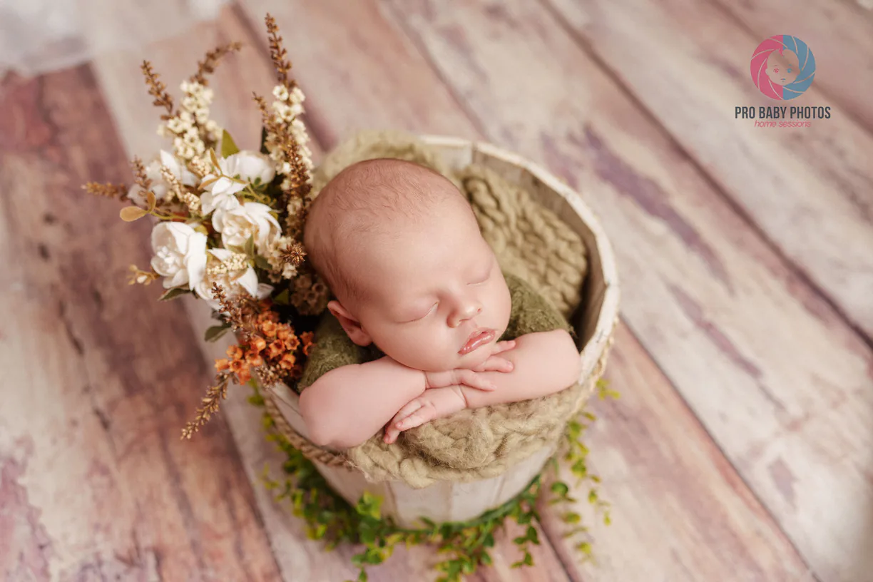 Sleeping baby in a green wrap and basket on a wooden floor