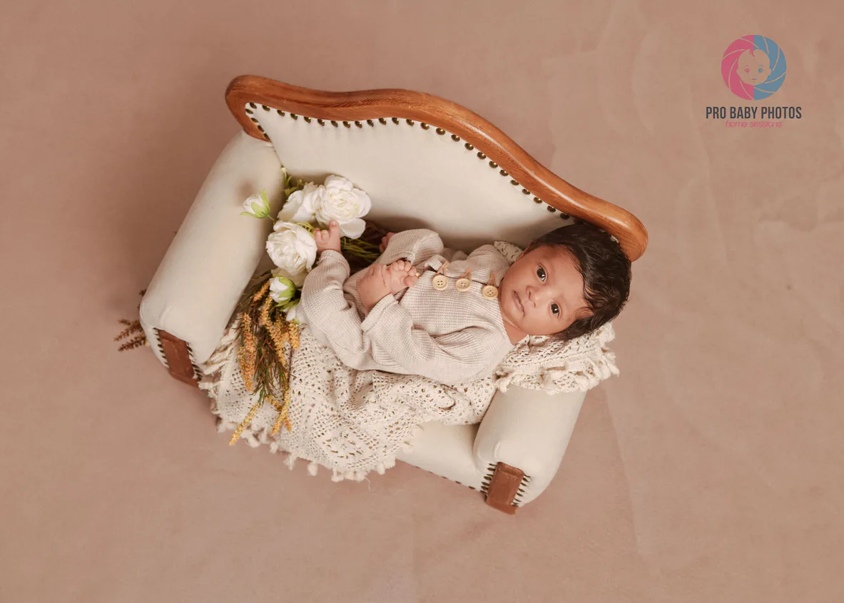Newborn baby reclining in a small upholstered chair