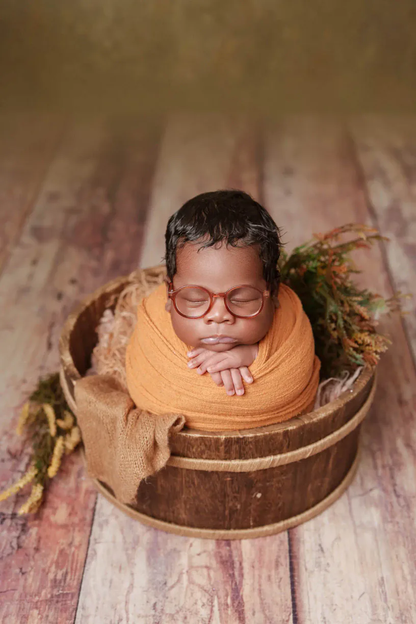 Baby resting in a rustic bucket with a warm yellow wrap