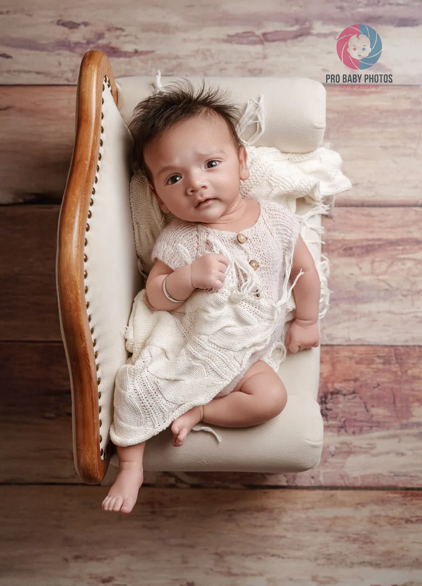 Baby lying in a small wooden bed on a textured blanket