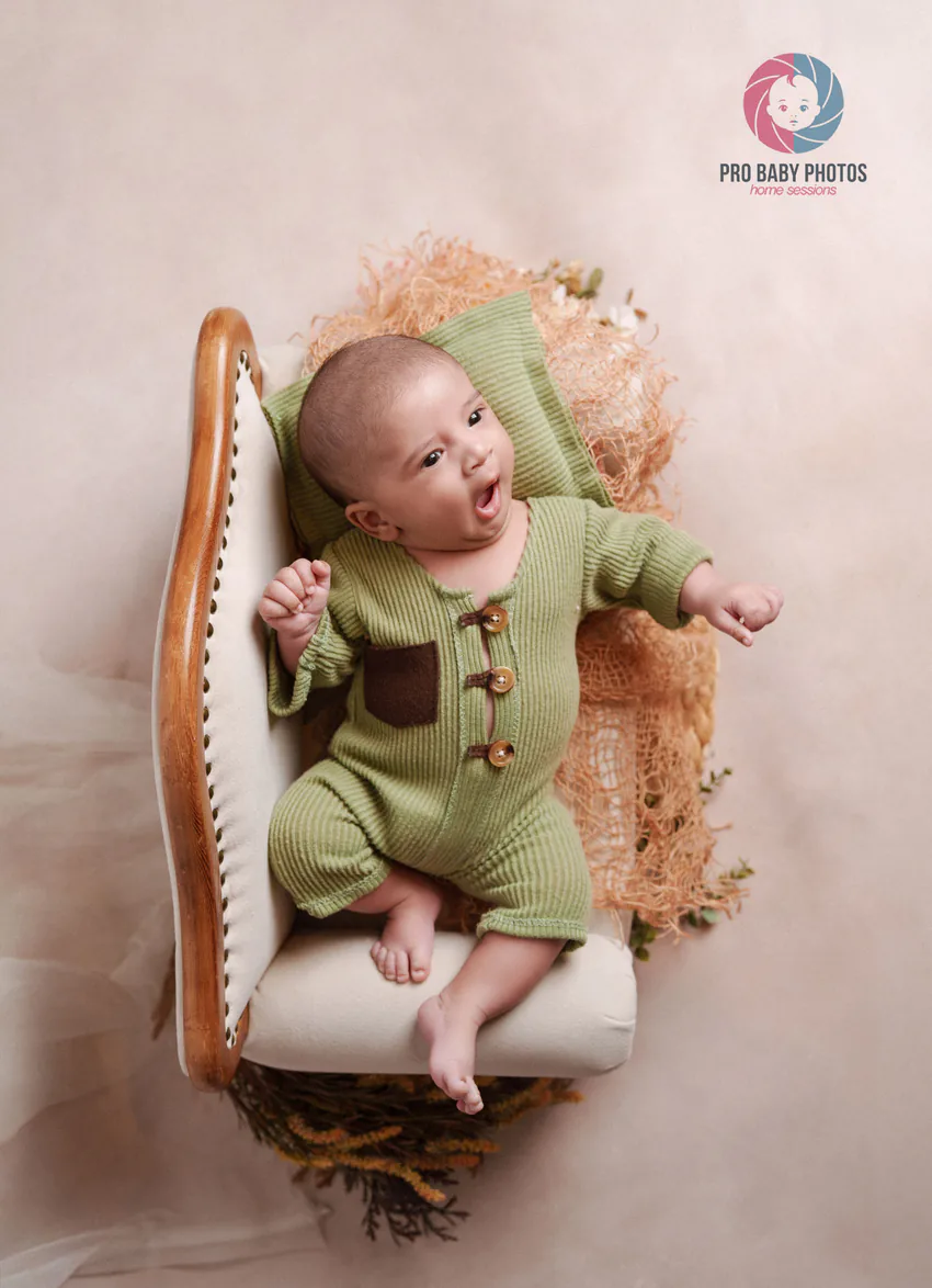 Baby in a green outfit resting in a small white seat