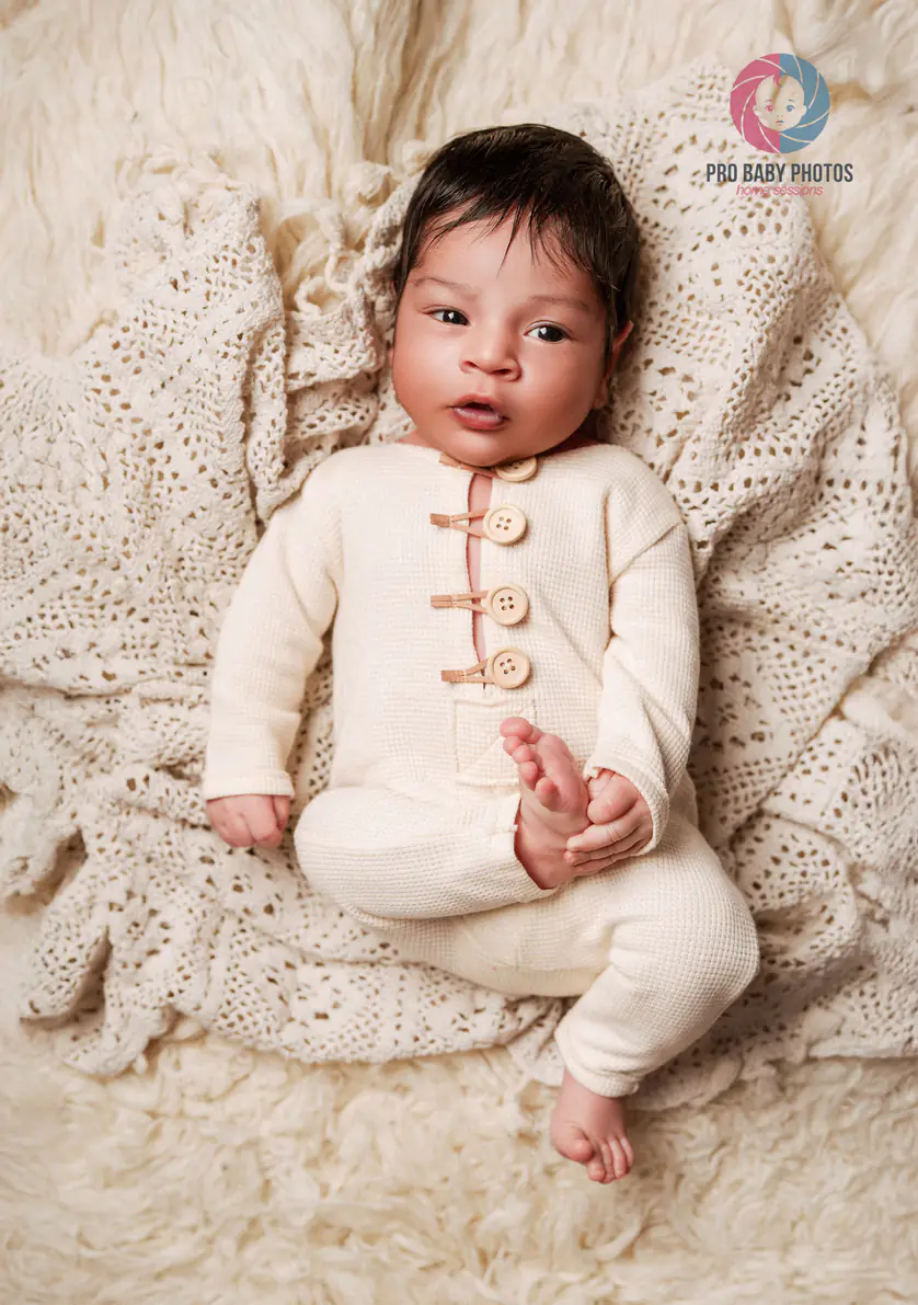Awake baby sitting against a cream textured blanket